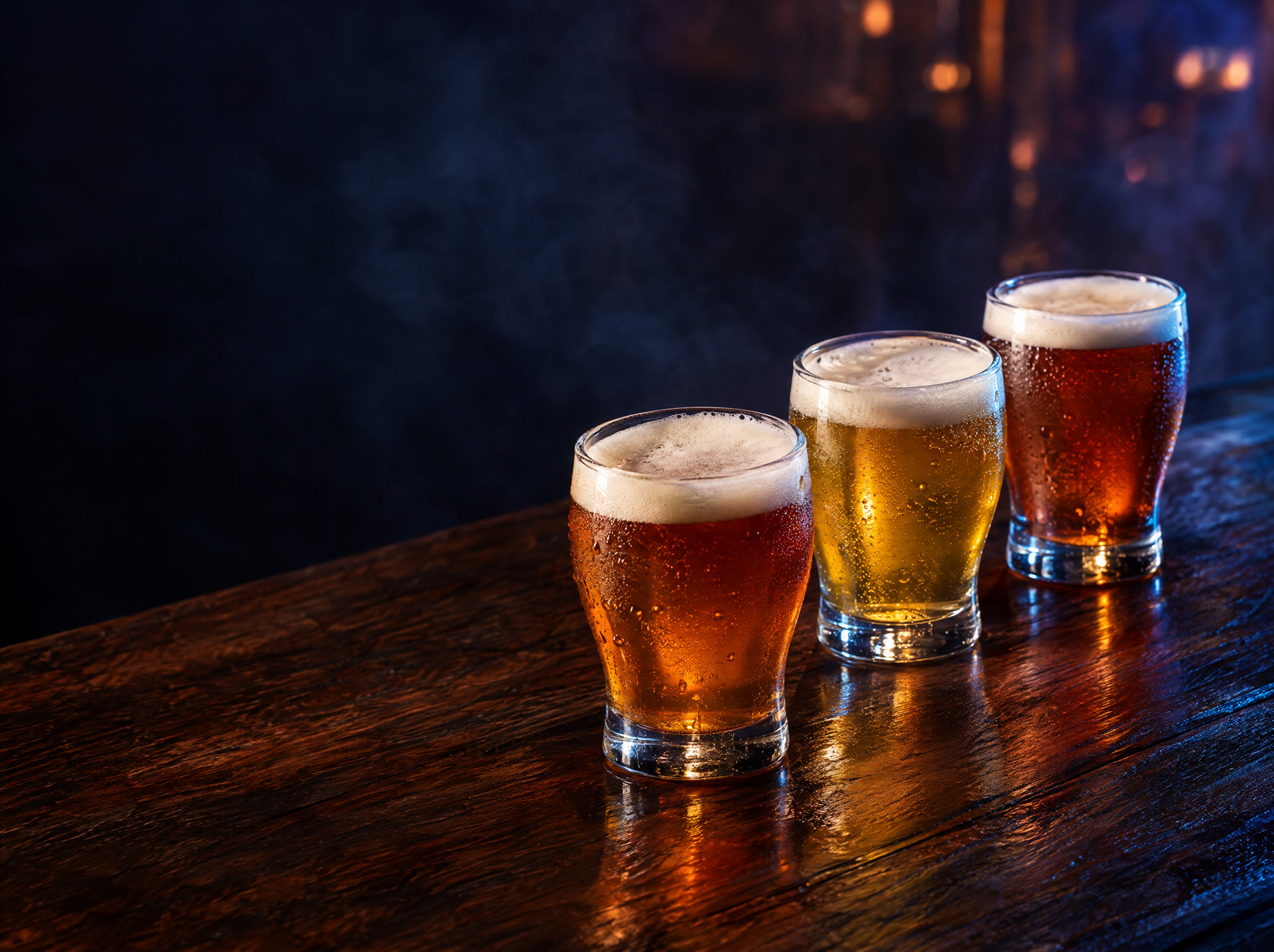 Três copos de cerveja artesanal em uma mesa de madeira